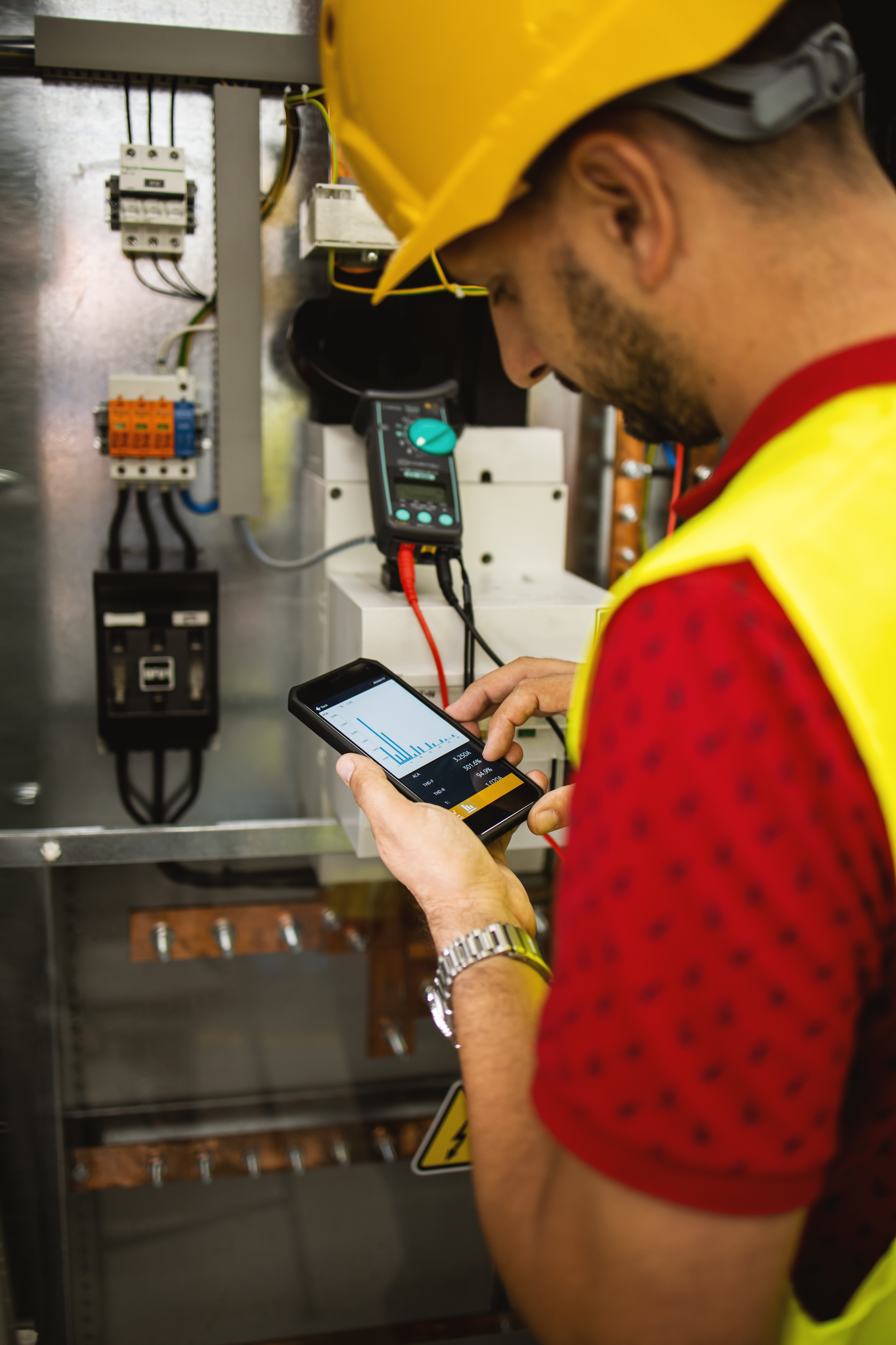 Electrician engineer work tester measuring voltage and current of power electric line in electical cabinet control.
